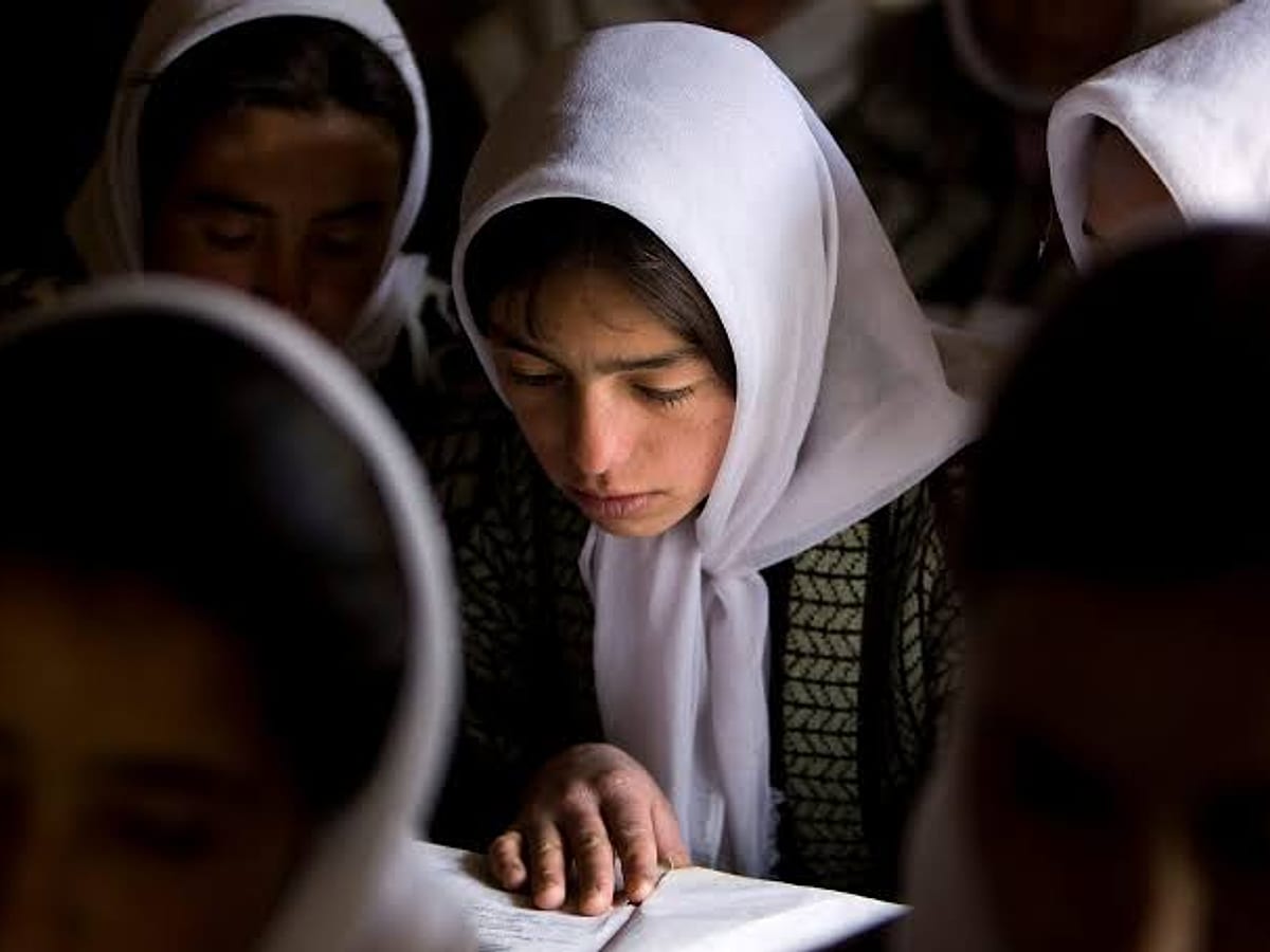 A girl in a white headscarf reading in class