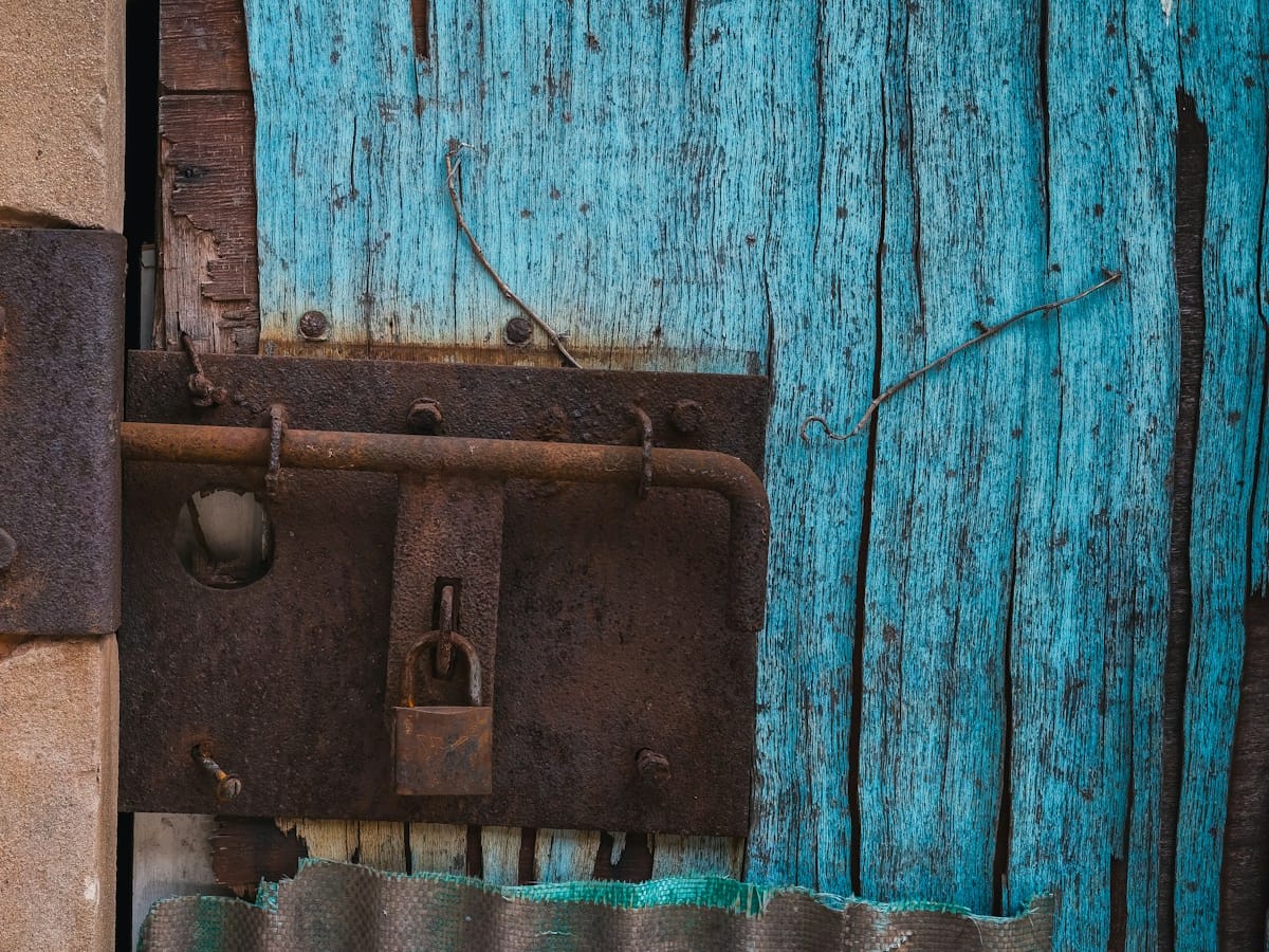 A rusty padlock on an old blue wooden door