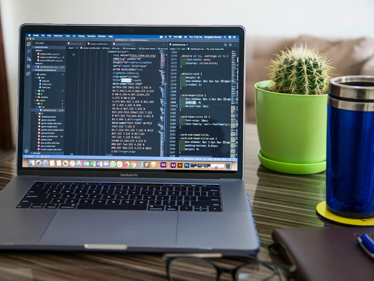 A laptop showing code on a desk beside a small cactus