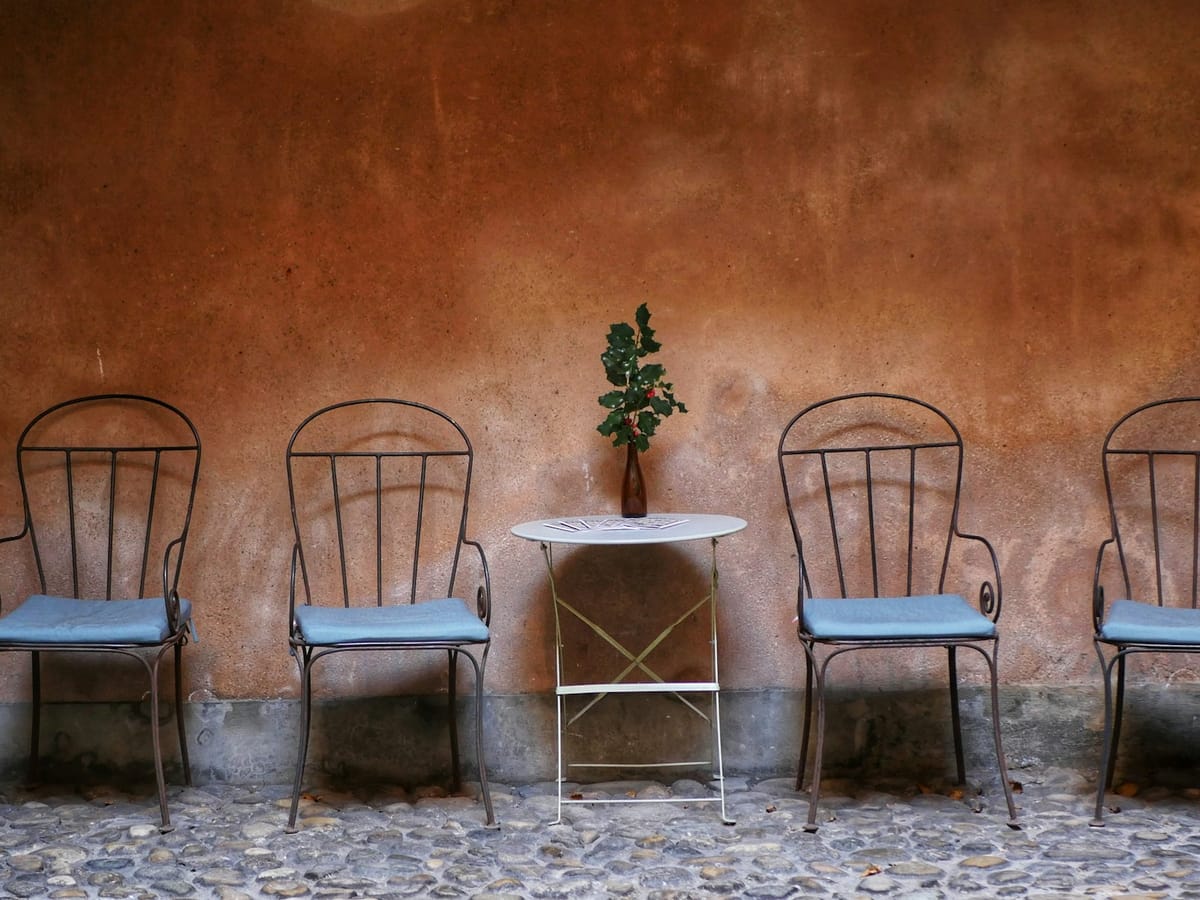 Four chairs and a small table against an earth-coloured wall